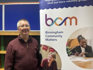 Chris Bonnard, smiling, standing beside BCM pull-up banner