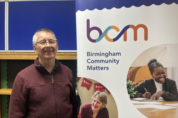 Chris Bonnard, smiling, standing beside BCM pull-up banner